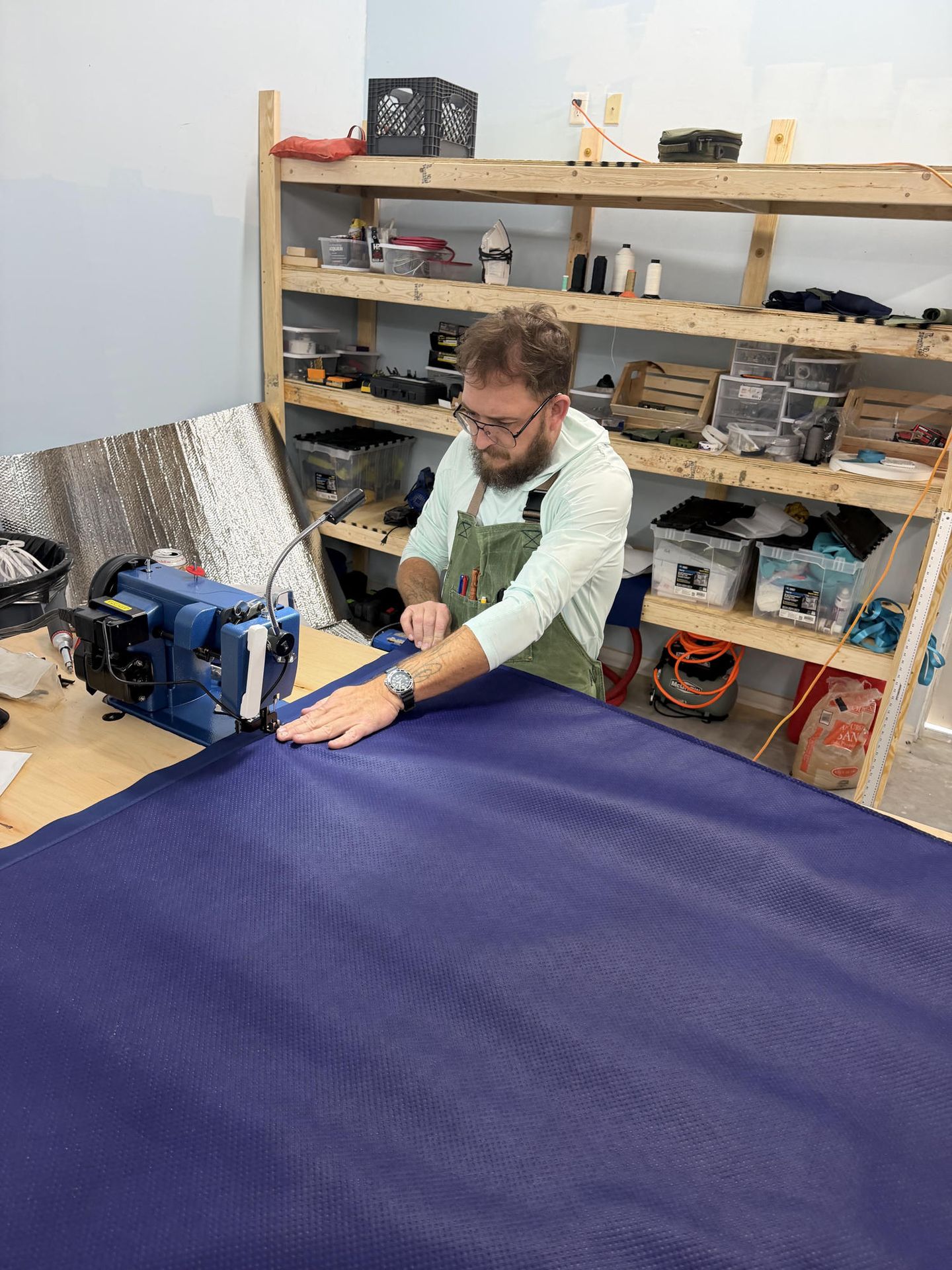 Sewing navy fabric on the loft floor at Bosun & Hawk